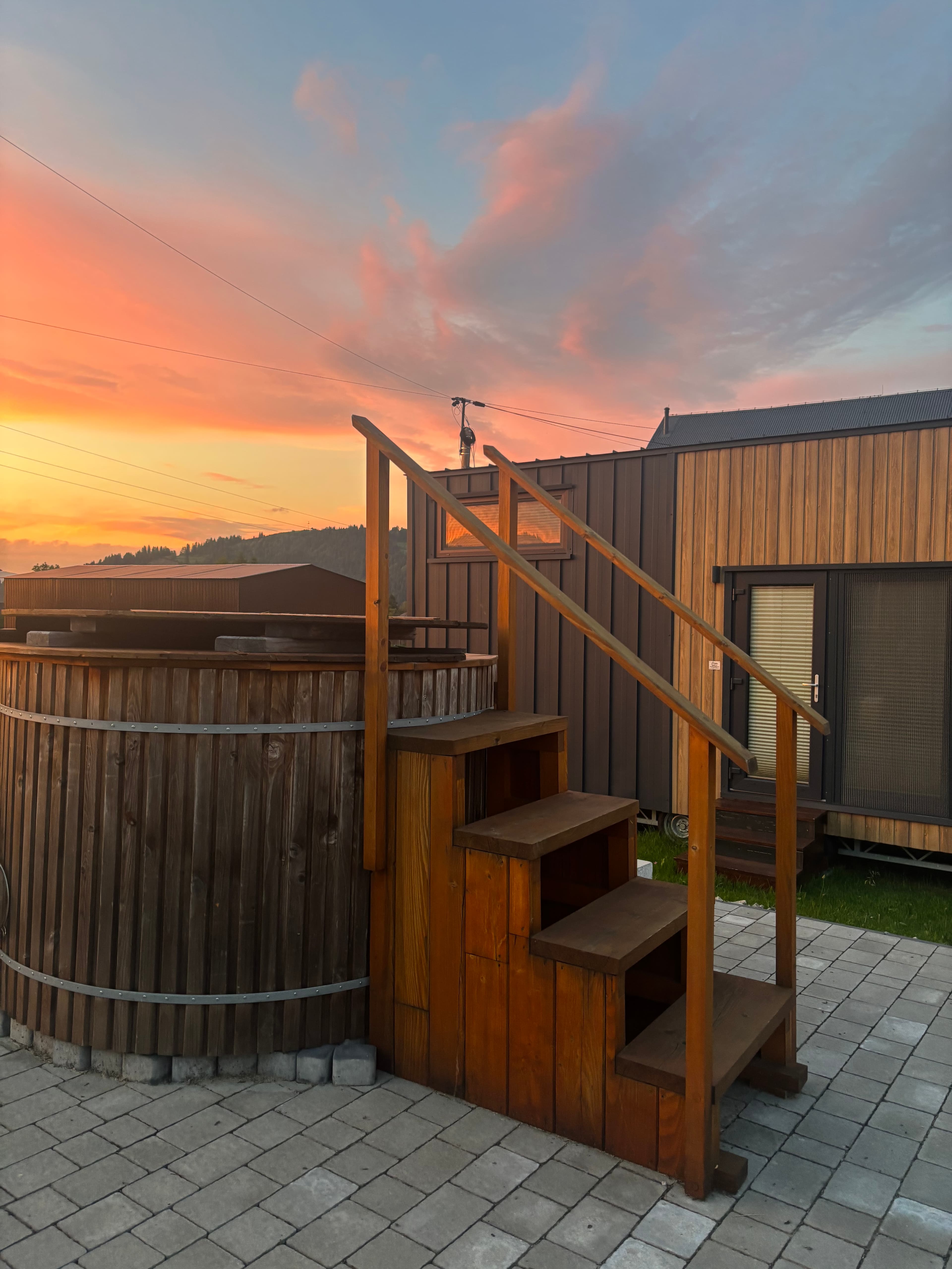 ClaudHouse cabin at sunset — patio with a hanging chair and mountain views